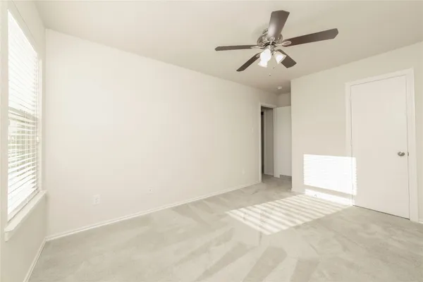 an empty room with windows and fan