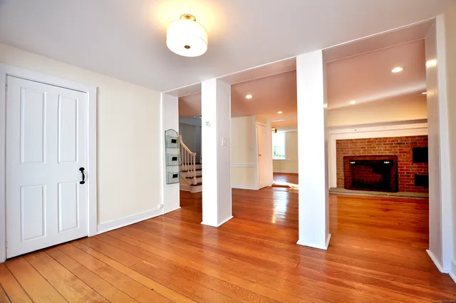 a view of an empty room with wooden floor and a fireplace