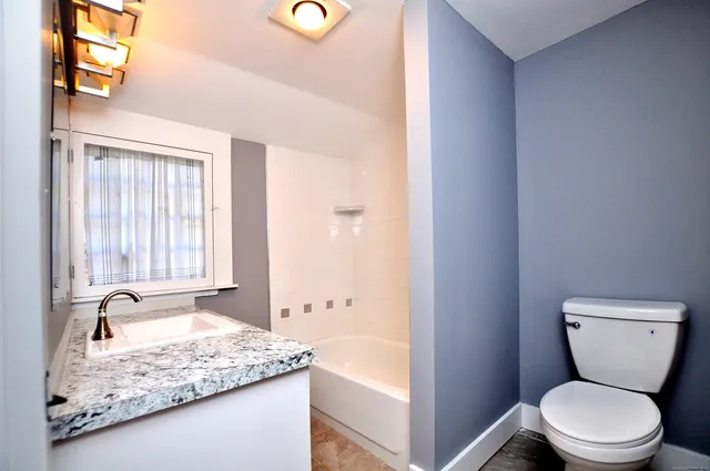 a bathroom with a granite countertop sink a toilet and bathtub