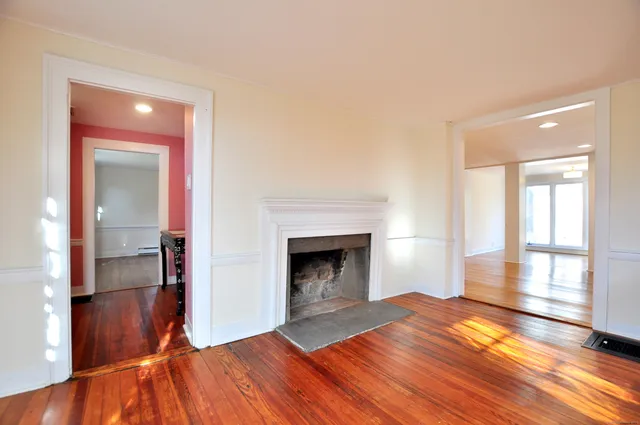 a view of empty room with wooden floor and fireplace