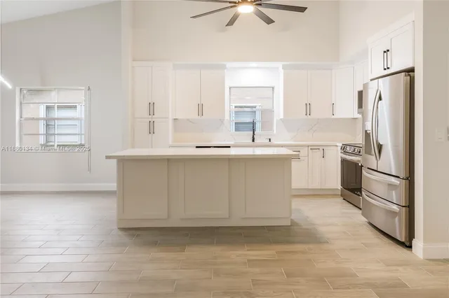 a kitchen with stainless steel appliances granite countertop a sink a stove a refrigerator and island with wooden floor