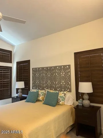 a bedroom with a bed lamp and table next to a window