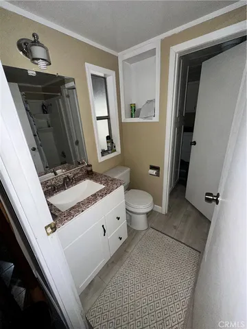 a bathroom with a granite countertop sink toilet and mirror
