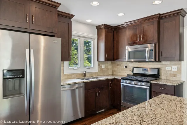 a kitchen with granite countertop a refrigerator stove and microwave