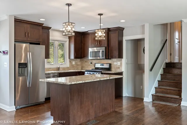 a kitchen with stainless steel appliances granite countertop a refrigerator a oven and a sink