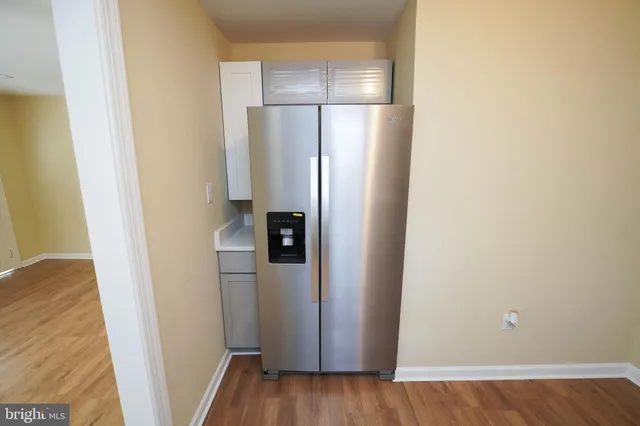 a view of a refrigerator in kitchen and an empty room