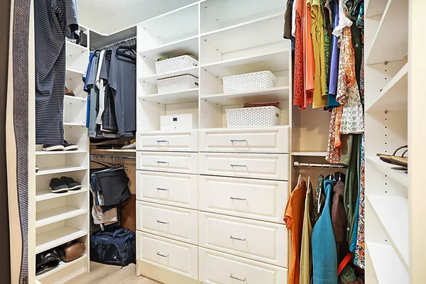 a view of walk in closet with clothes and shoes