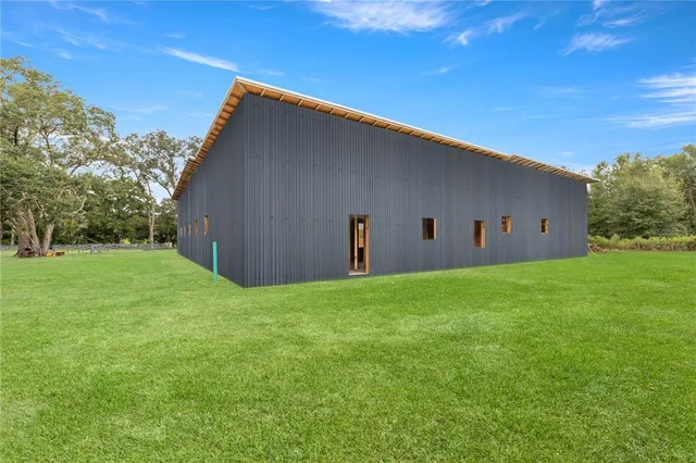 a view of a house with a yard plants and large tree