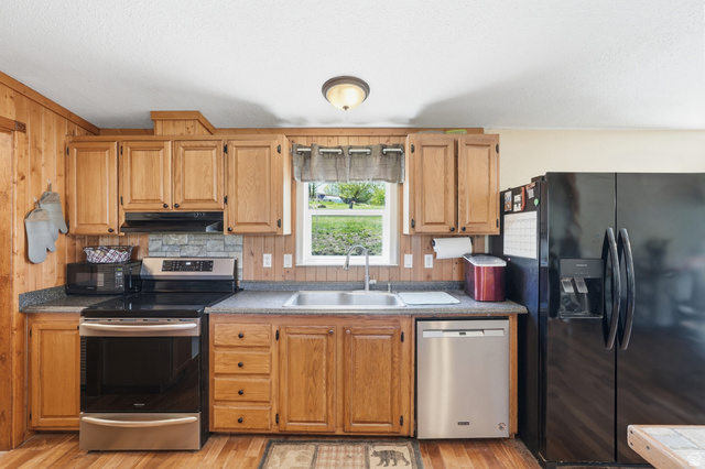 8066 North Valley View Heights Preston, ID 83263 - Photo 15 of 34 Kitchen featuring wood-finish paneling, wood-finish cabinetry, a stainless steel electric range, a stainless steel dishwasher, and a double basin sink
