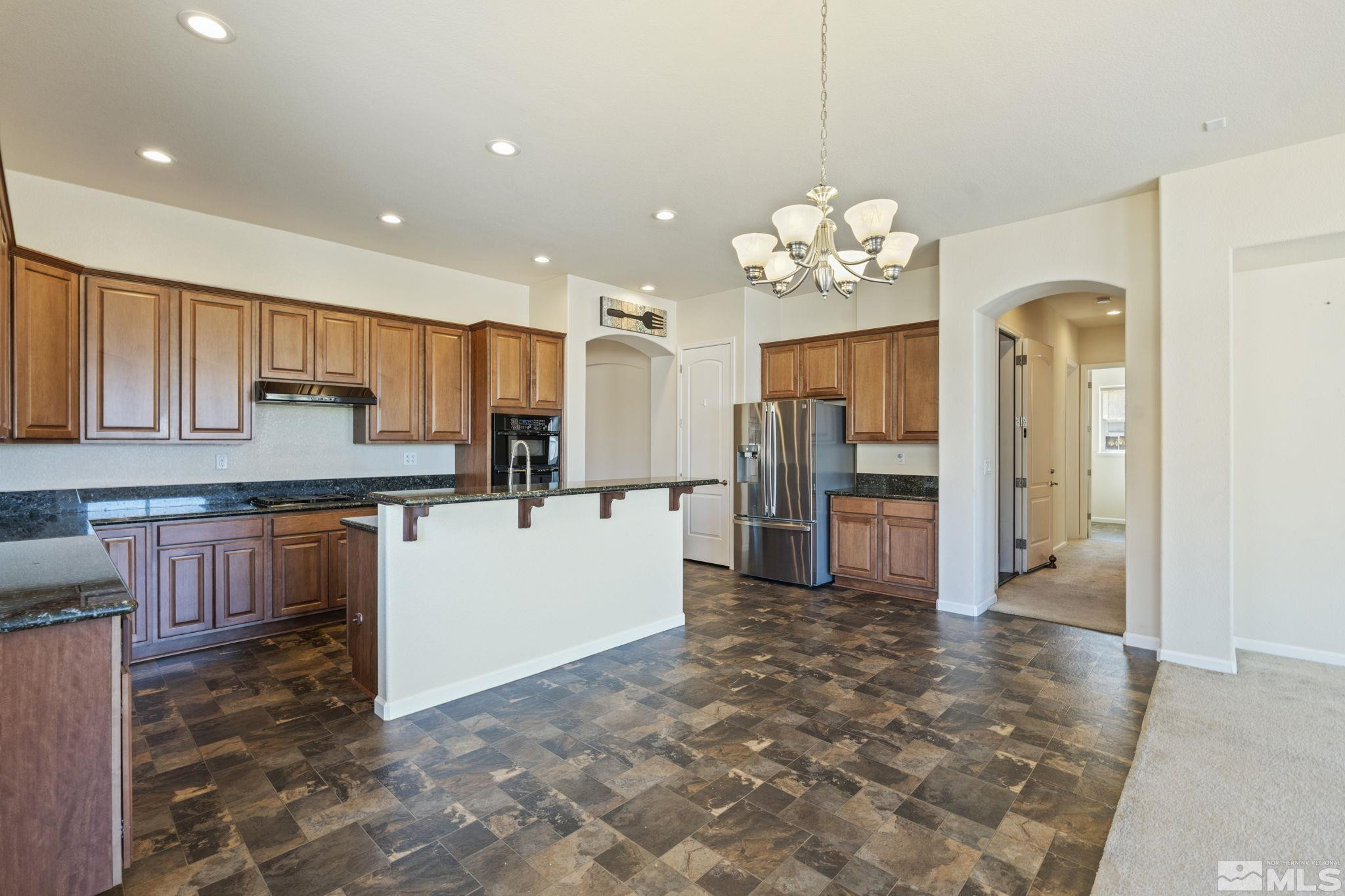 10295 Cavalry Circle Reno, NV 89521 - Photo 13 of 40 a kitchen with kitchen island granite countertop wooden cabinets a refrigerator and a stove