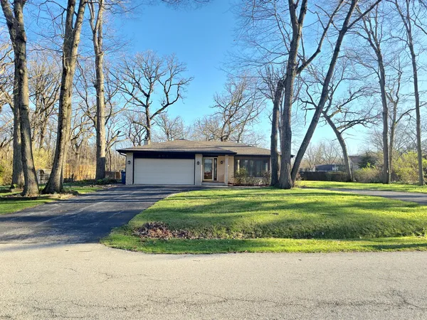a front view of a house with a garden and trees