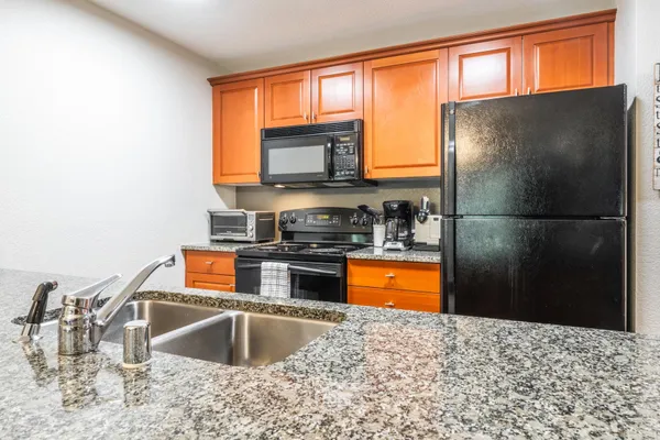 a kitchen with stainless steel appliances granite countertop a refrigerator a stove and a sink with granite countertops