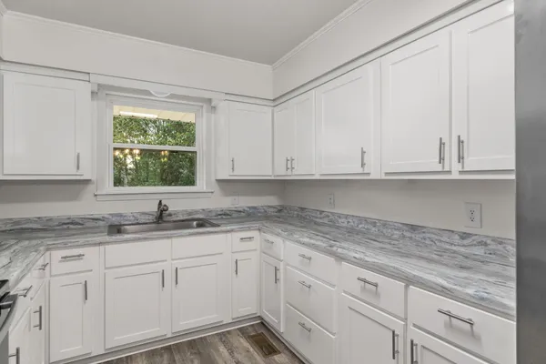 a kitchen with granite countertop white cabinets and a window
