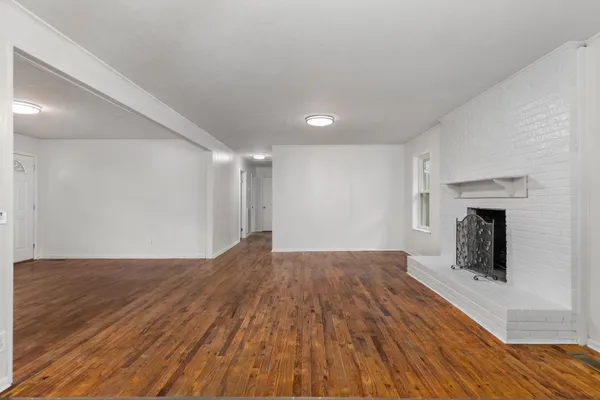 a view of empty room with wooden floor and fireplace