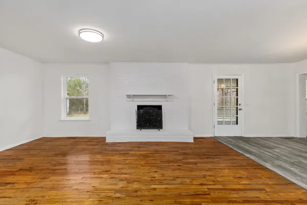 a view of an empty room with window and wooden floor