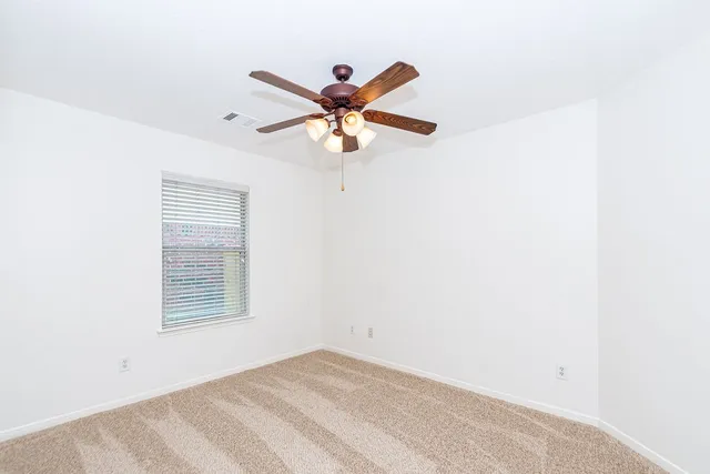 a view of a room with a ceiling fan and a window