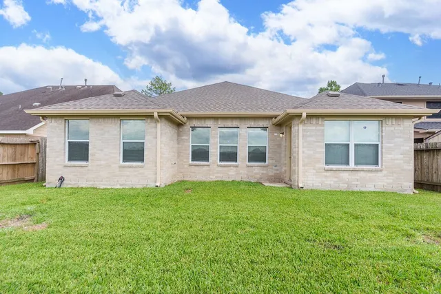 a view of a house with a yard and a large tree