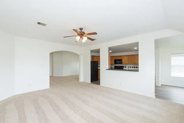a view of an empty room with window and wooden floor
