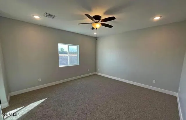 an empty room with a ceiling fan and window
