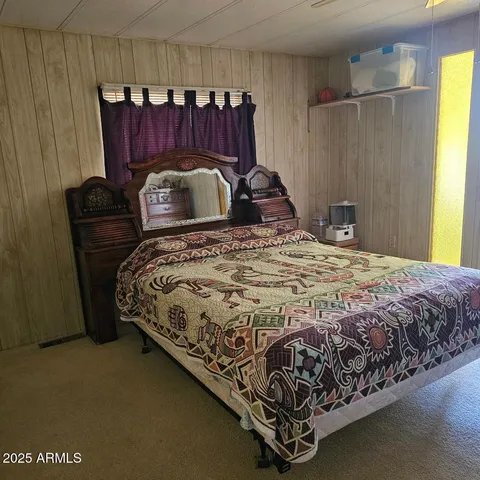 a bed sitting in a bedroom next to a window and a wooden chair