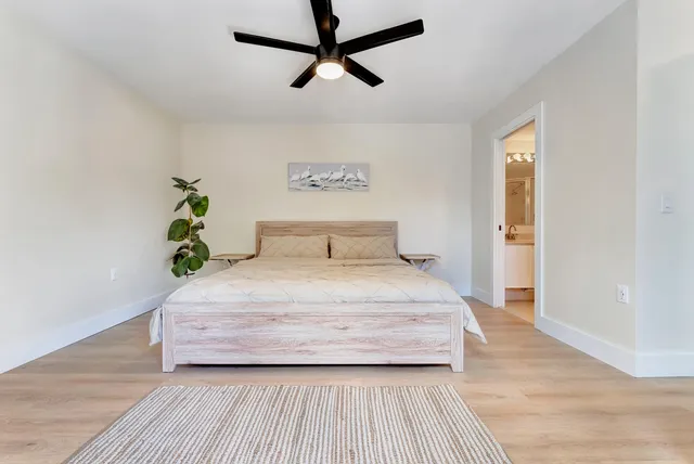 a bedroom with a bed a flat screen tv and a ceiling fan
