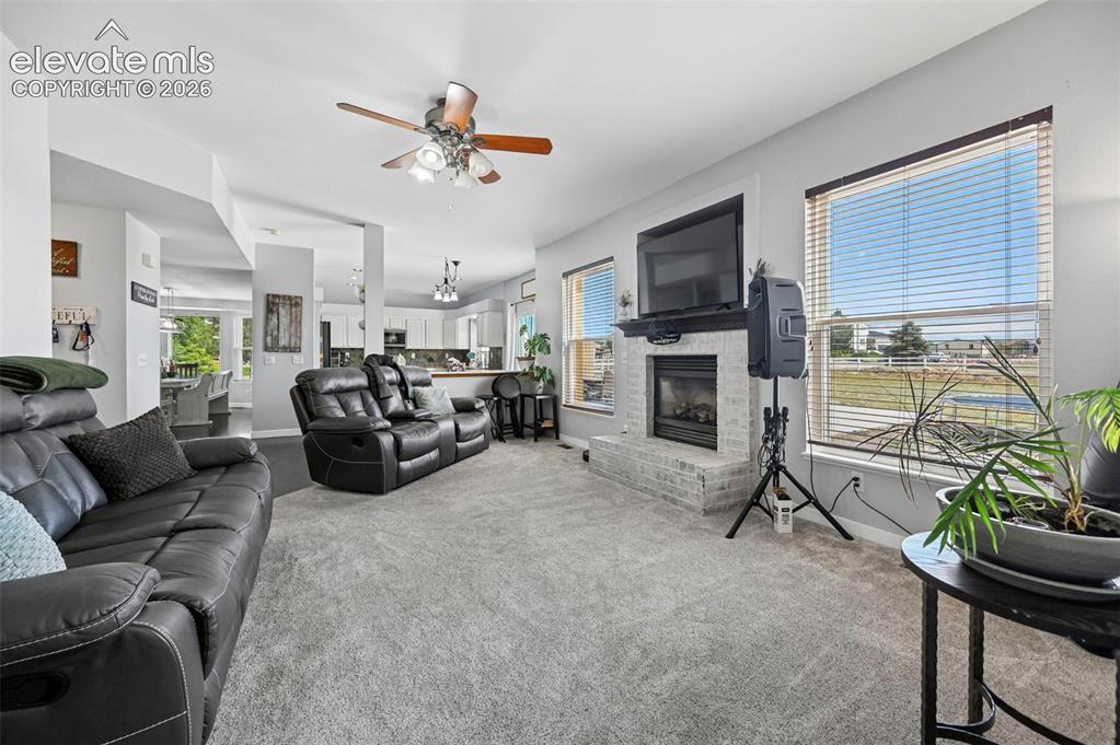 8347 Tibbs Road Peyton, CO 80831 - Photo 22 of 39 Living area featuring light gray carpeting and a white brick fireplace with a dark mantel