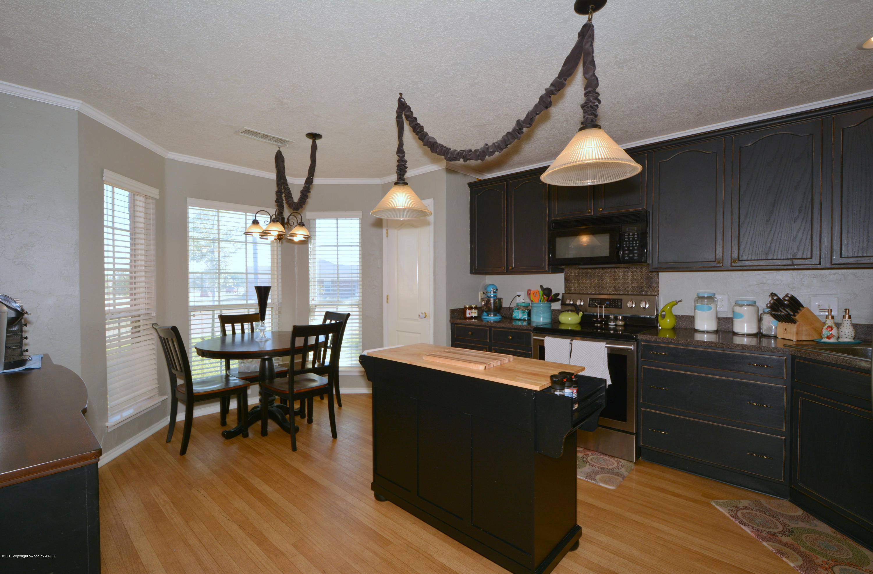 4702 Capulin Lane Amarillo, TX 79110 - Photo 6 of 24 a kitchen with granite countertop a dining table chairs stove and cabinets