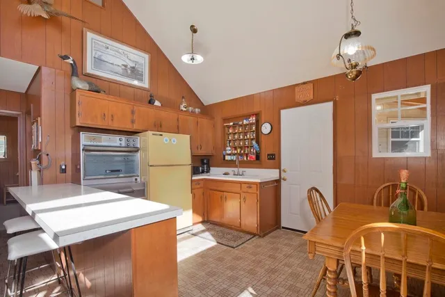 a kitchen with stainless steel appliances kitchen island granite countertop a table chairs in it and wooden floors