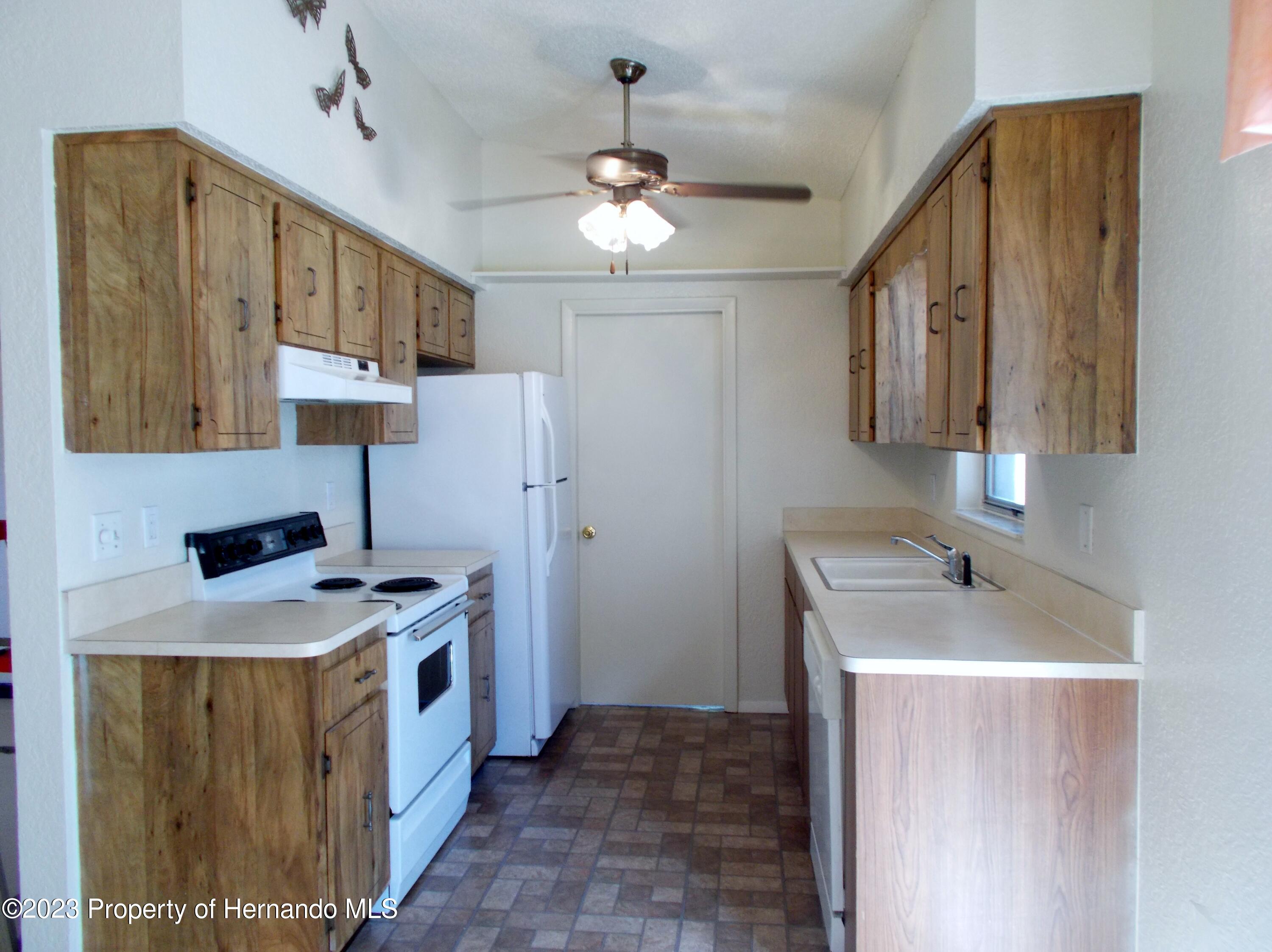 10340 Musa Road Spring Hill, FL 34608 - Photo 3 of 16 a kitchen that has a sink a stove and a refrigerator
