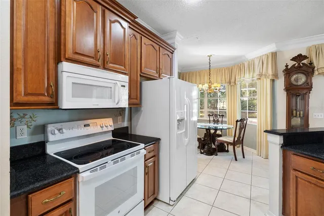 a kitchen with granite countertop a stove a refrigerator and wooden cabinets