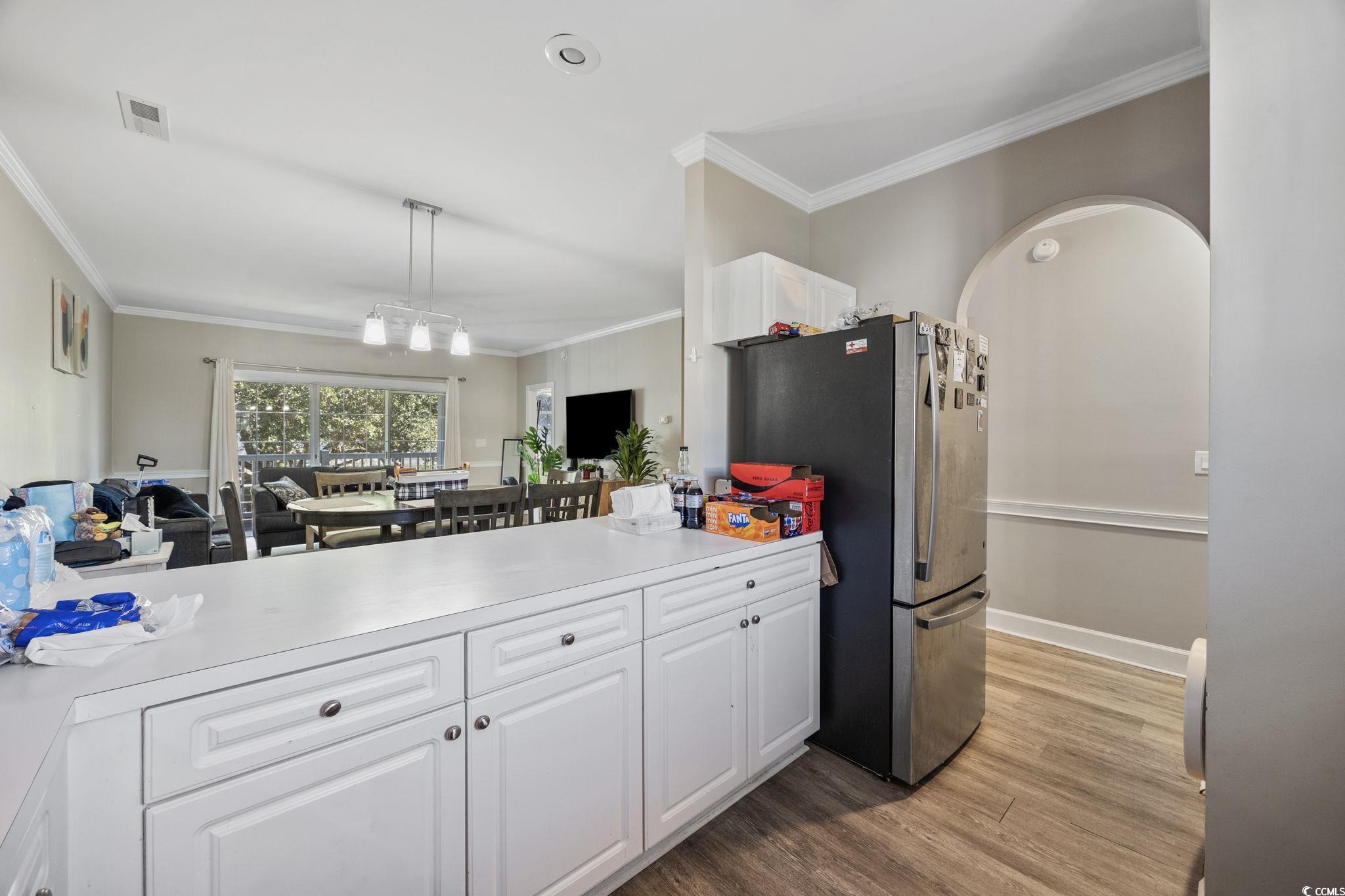 4639 Wild Iris Drive, Unit 203 Myrtle Beach, SC 29577 - Photo 11 of 30 Kitchen featuring light countertops, white cabinets, ornamental molding, pendant lighting, and dark wood-type flooring