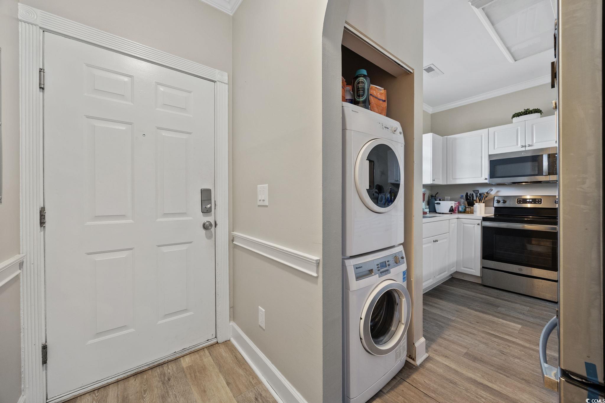 4639 Wild Iris Drive, Unit 203 Myrtle Beach, SC 29577 - Photo 12 of 30 Laundry room featuring crown molding, light wood finished floors, and stacked washer / drying machine
