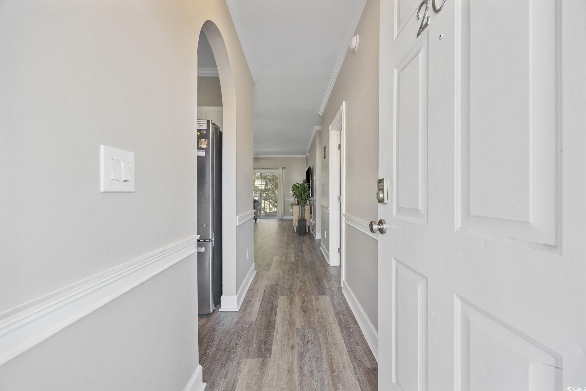 4639 Wild Iris Drive, Unit 203 Myrtle Beach, SC 29577 - Photo 3 of 30 Hallway featuring light wood-style floors, arched walkways, and ornamental molding