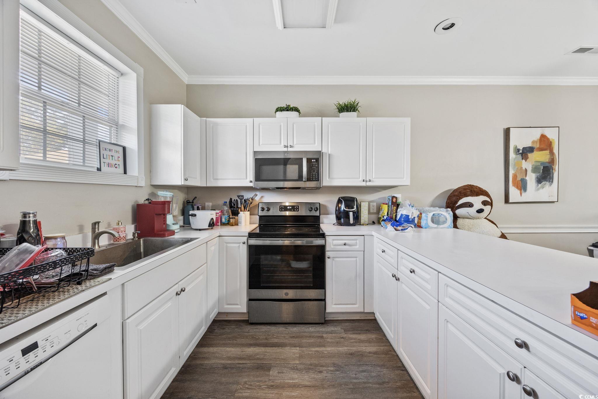 4639 Wild Iris Drive, Unit 203 Myrtle Beach, SC 29577 - Photo 10 of 30 Kitchen featuring white cabinetry, ornamental molding, stainless steel appliances, and light countertops