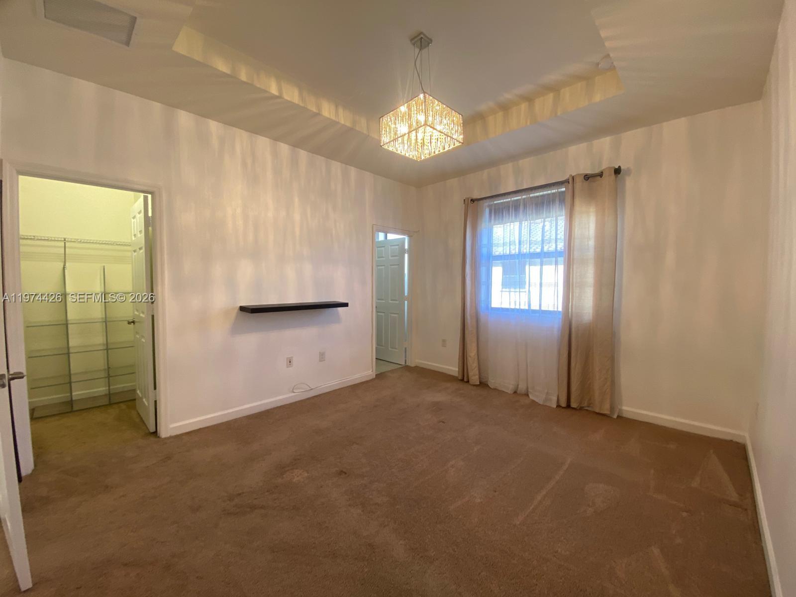 11543 Southwest 248th Lane Homestead, FL 33032 - Photo 19 of 32 an empty room with chandelier fan and windows