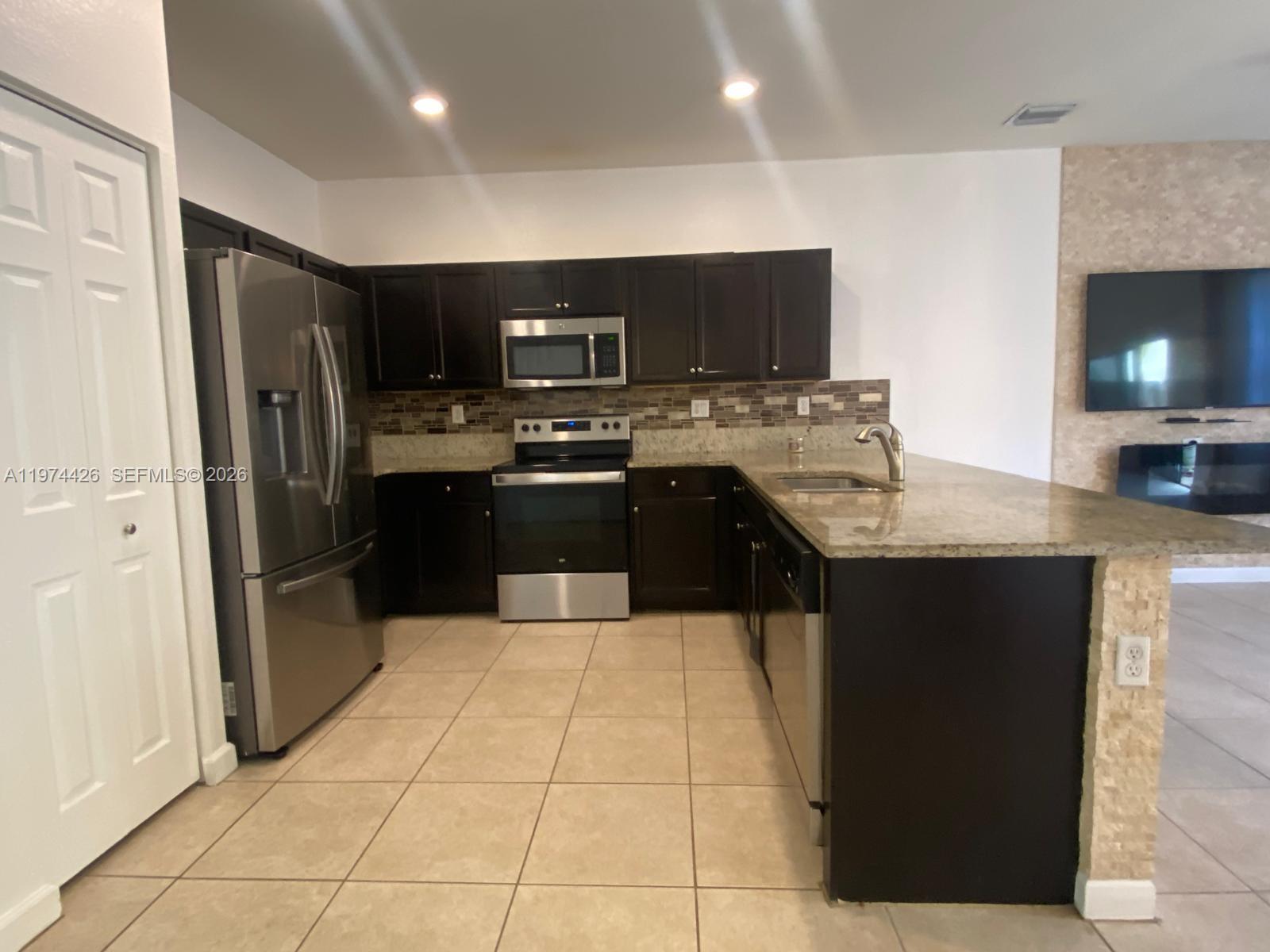 11543 Southwest 248th Lane Homestead, FL 33032 - Photo 4 of 32 a large kitchen with a counter top space a refrigerator and a sink