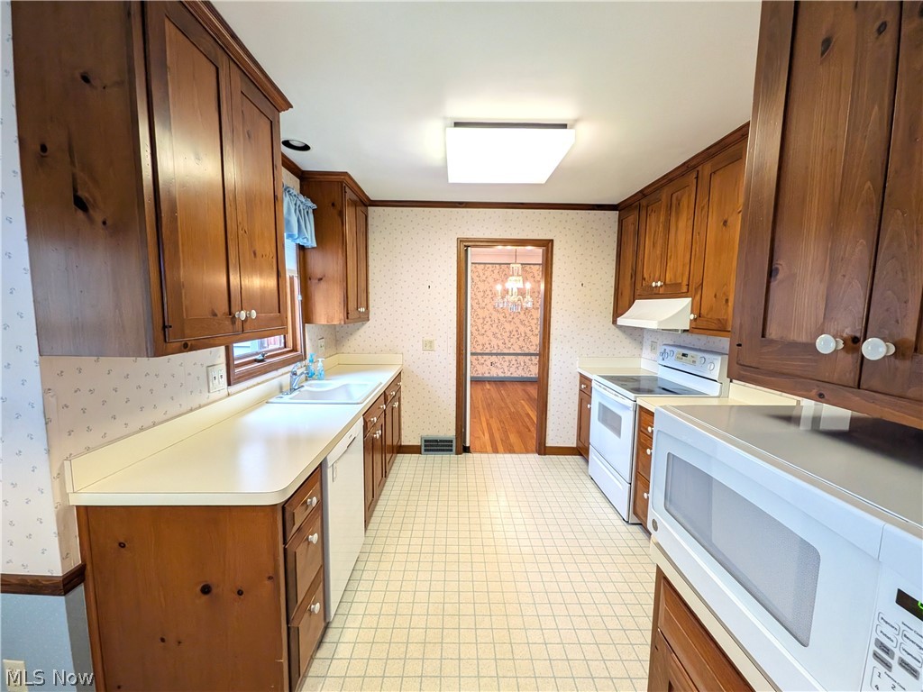 2316 Glendon Road Cleveland, OH 44118 - Photo 9 of 22 Kitchen featuring white appliances, wood finish cabinetry, wallpapered walls, and ornamental molding