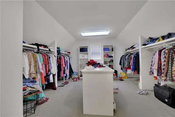 a view of walk in closet with clothes and shoes