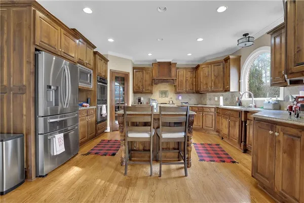 a kitchen with stainless steel appliances a dining table chairs stove refrigerator and cabinets