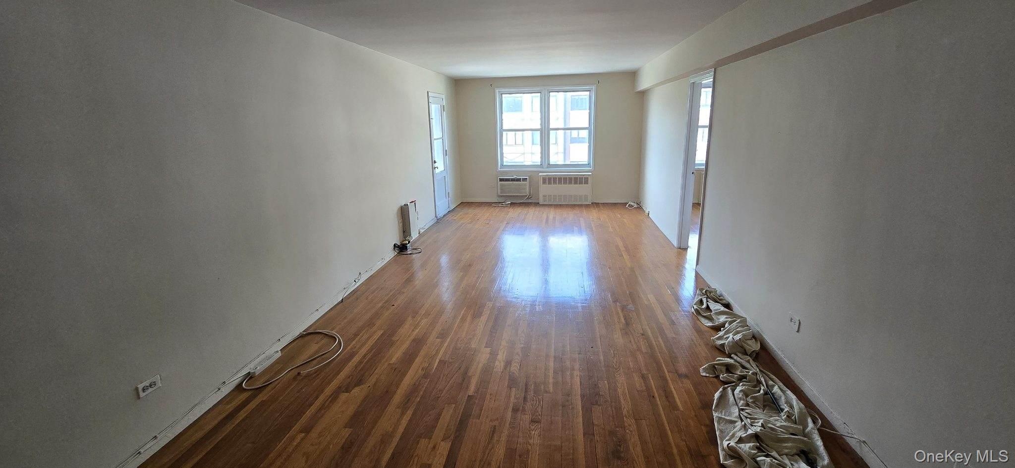 241-20 Northern Boulevard, Unit 4C Queens, NY 11362 - Photo 4 of 12 wooden floor in an empty room with a window