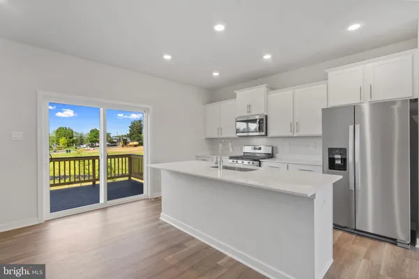 a kitchen with stainless steel appliances granite countertop a refrigerator a stove a sink and a large window
