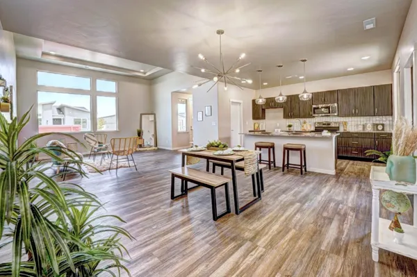 a living room with lots of furniture wooden floor and kitchen view