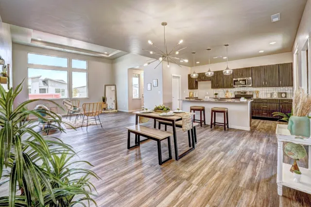 a living room with lots of furniture wooden floor and kitchen view