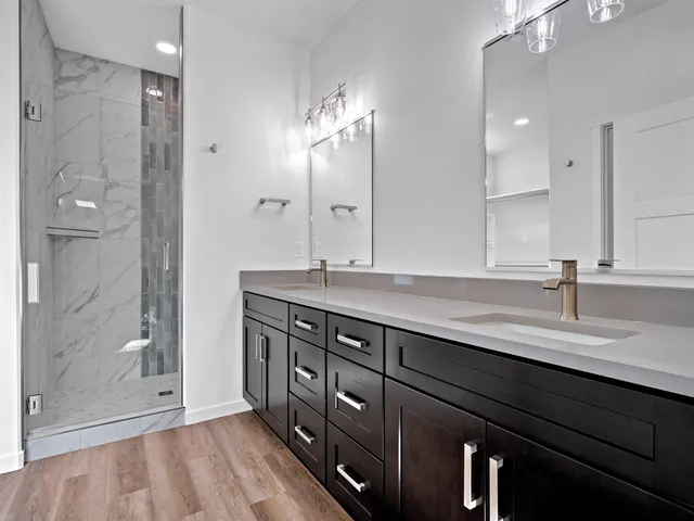 a bathroom with a granite countertop sink a large mirror and shower
