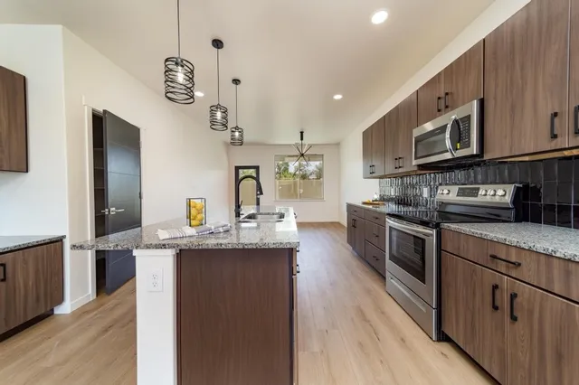 a kitchen with stainless steel appliances granite countertop a sink stove and refrigerator
