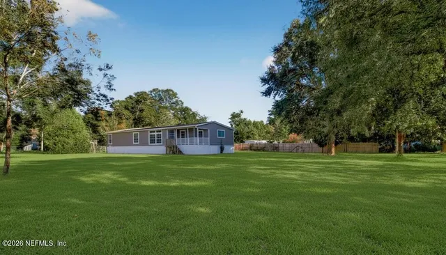 a view of a house with backyard and a tree
