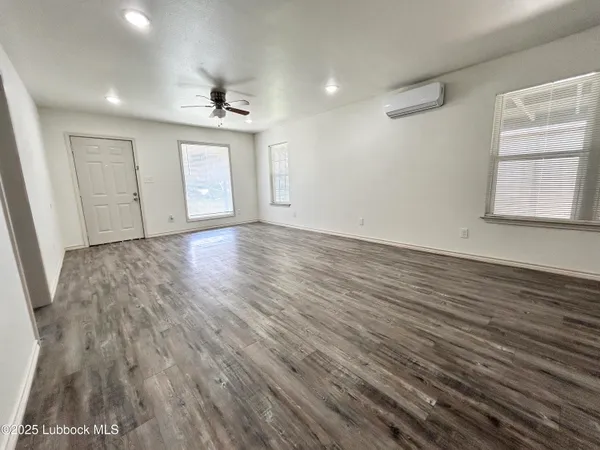 an empty room with wooden floor cabinet and windows