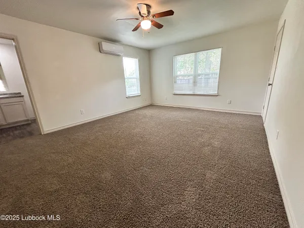 an empty room with windows and fan
