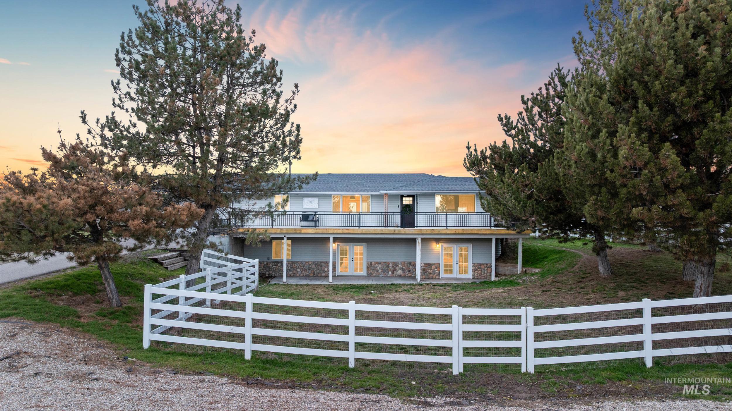 View of front of house featuring french doors, stone siding, a fenced front yard, and a patio area