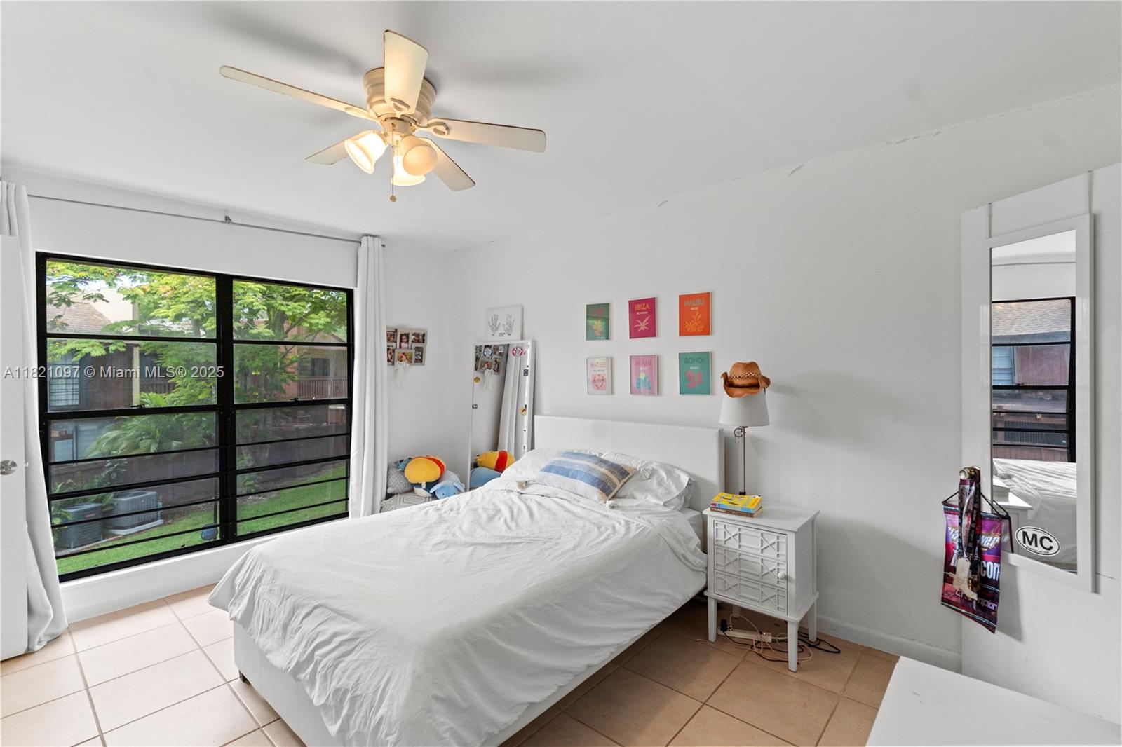 7074 Southwest 114th Place, Unit H Miami, FL 33173 - Photo 28 of 38 a bedroom with a bed and a chandelier